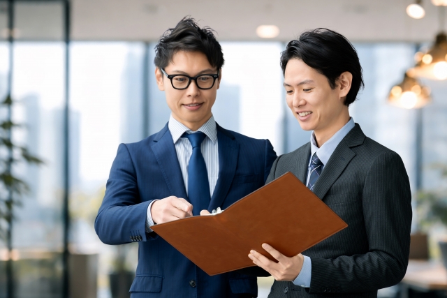 スーツ姿の2名が明るいオフィスまたは会議室で握手をしている。日米交流のイメージ